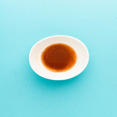 White bowl with brown liquid on a light blue background