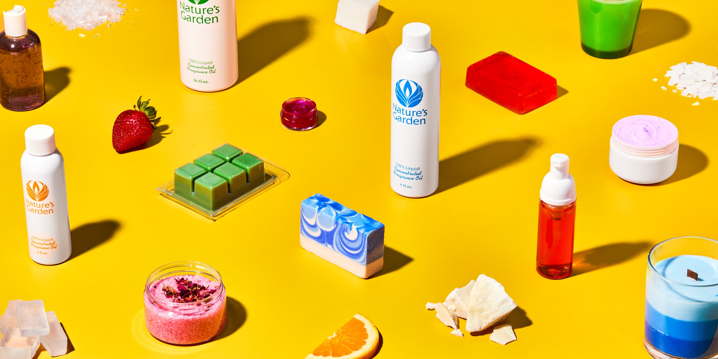 Nature’s Garden DIY supplies on yellow background, including fragrance oil bottles, colorful soap bars, whipped body butter, bath salts with dried flowers, wax melts, layered candle, foaming wash, strawberry, and orange slice.