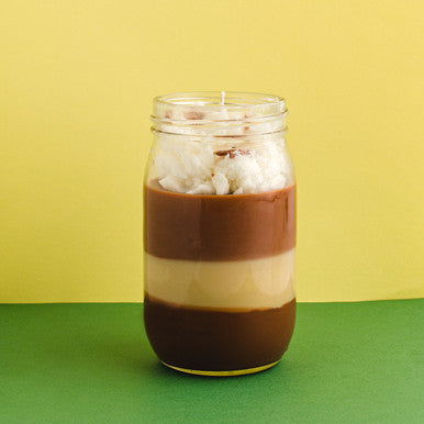 Layered iced coffee in a glass jar with a yellow background