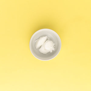 White cream in a small white bowl on a yellow background