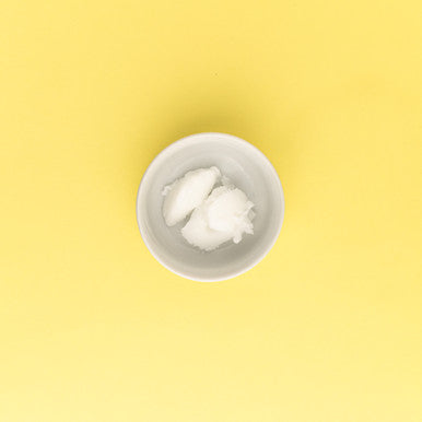White cream in a small white bowl on a yellow background