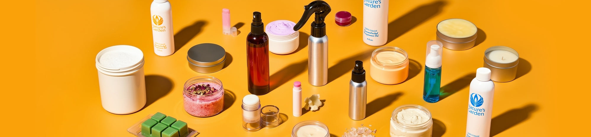 Assorted skincare and home care products arranged on a bright yellow background: jars of cream, spray and pump bottles, lip balms, scrub, candles, and wax cubes casting sharp shadows.