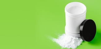 White container of carpet freshener powder with the lid off, showing fine white powder spilling onto the surface, set against a bright green background.