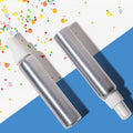 Two silver spray bottles with white nozzles on a blue and multicolored confetti background