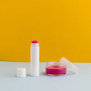 Lip balm and container on a yellow and gray background