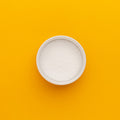 White bowl filled with white powder on a yellow background