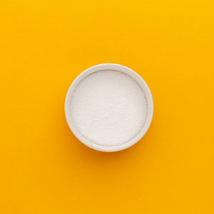 White bowl filled with white powder on a yellow background
