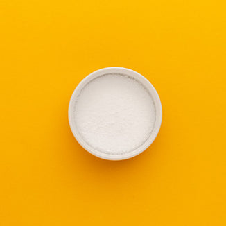 White bowl filled with white powder on a yellow background