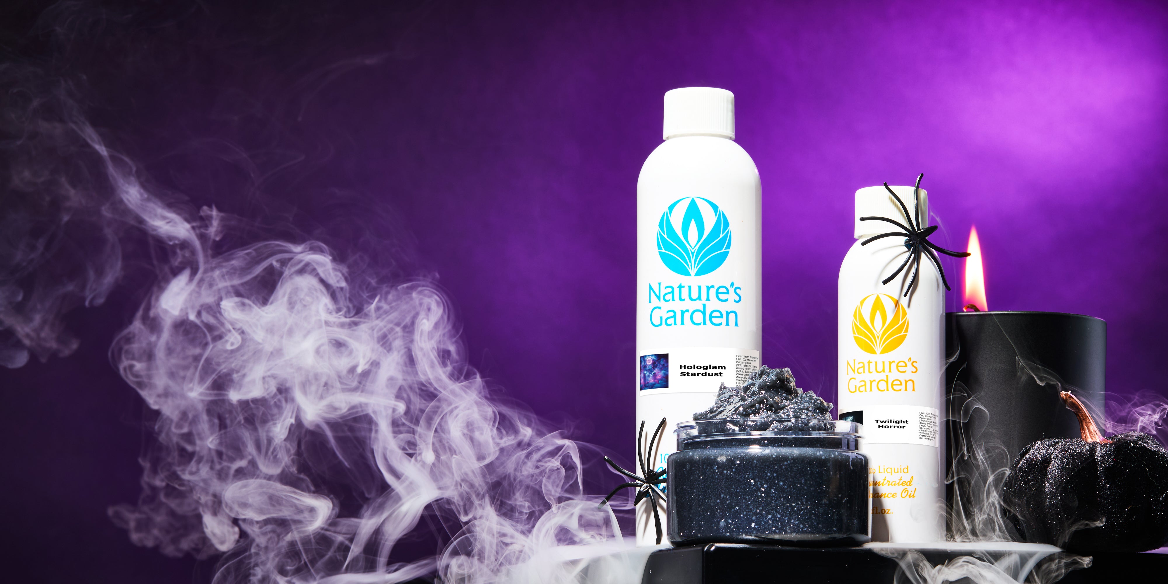 Nature’s Garden Hologlam Stardust and Twilight Horror fragrance oils displayed with black spiders, smoky fog, a candle flame, and glittery Halloween décor against a purple background.