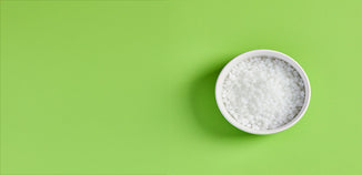 White BTMS 50 pellets in a round white bowl on a bright green background.
