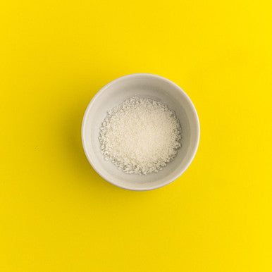 White bowl with salt on a yellow background