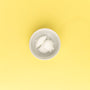 White cream in a small white bowl on a yellow background