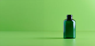 Empty dark green glass cosmetic bottle on a light green background.