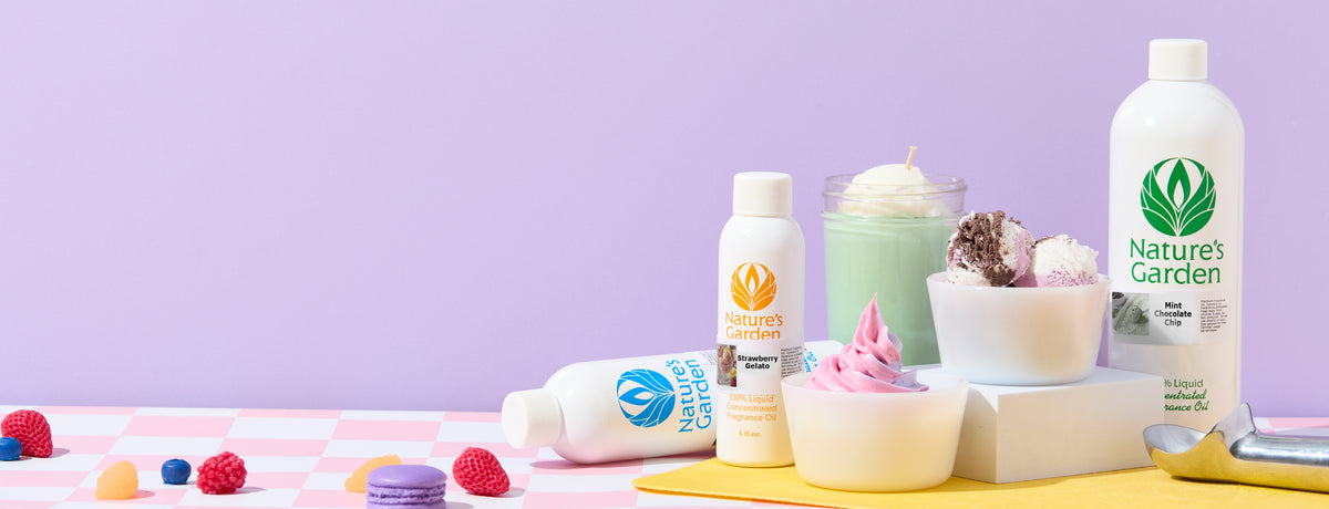 Nature's Garden fragrance oil bottles in Strawberry Gelato, Mint Chocolate Chip, and a blue-labeled variety displayed with pastel ice cream scoops, soft-serve, a mint-green candle, colorful candy, and an ice cream scoop on a pink checkered surface against a lavender background.