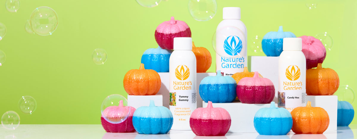 Bright pink, blue, and orange pumpkin-shaped candles arranged around Nature’s Garden fragrance oil bottles against a lime green background with floating bubbles.
