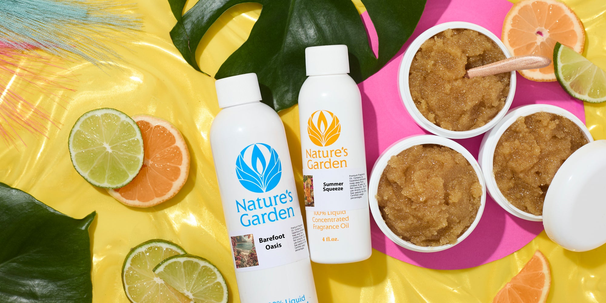 Nature's Garden fragrance oil bottles with citrus slices, tropical leaves, and open jars of sugar scrub on bright yellow and pink backgrounds, creating a vibrant summer-inspired product display.